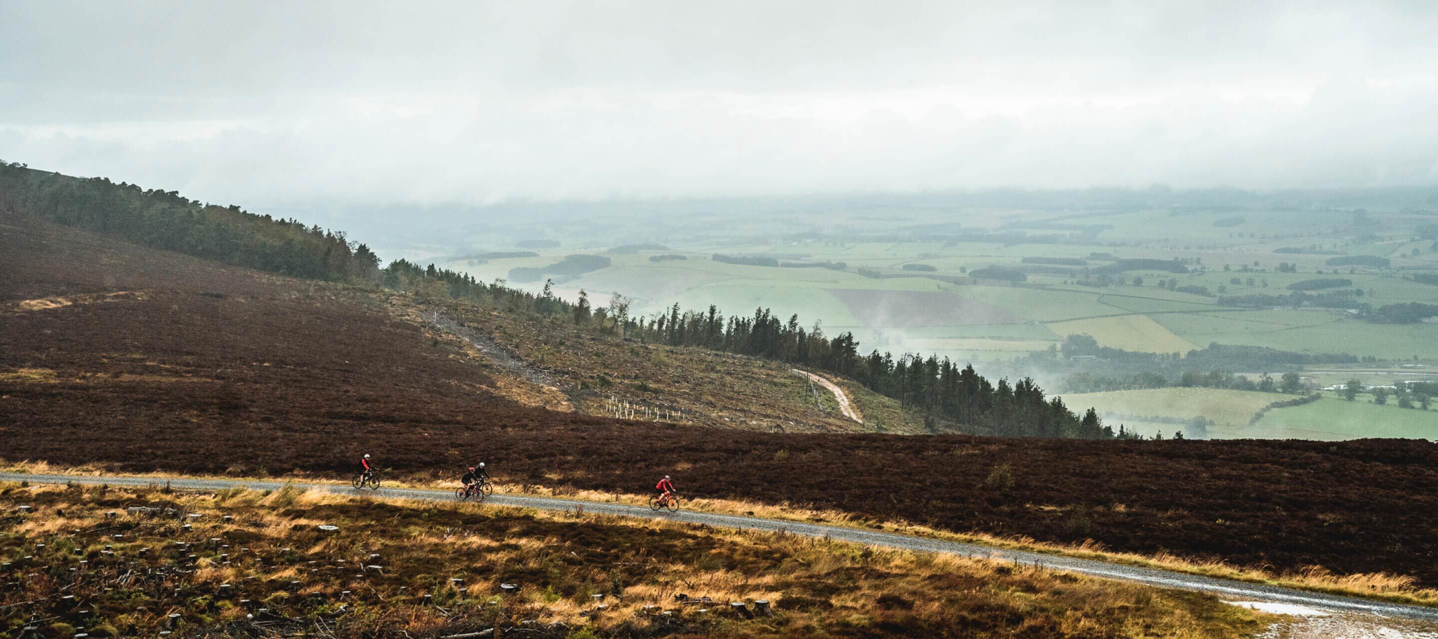 Cyclists riding on wet gravel road in light fog