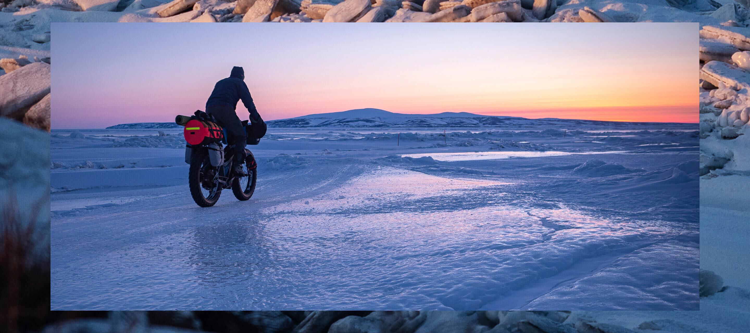 Cyclist riding fat bike loaded with gear, and pannier bags riding on Iditarod trail at sunset