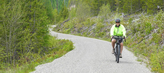 Cyclist riding Salsa Tributary ebike on remote forest gravel road