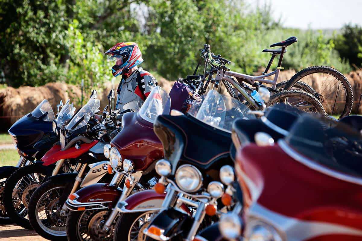 Motorcyclist in protective gear parking alongside several other parked motorcycles