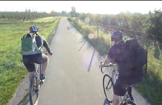 Two cyclists ride together on a paved trail on their drop bar bikes.