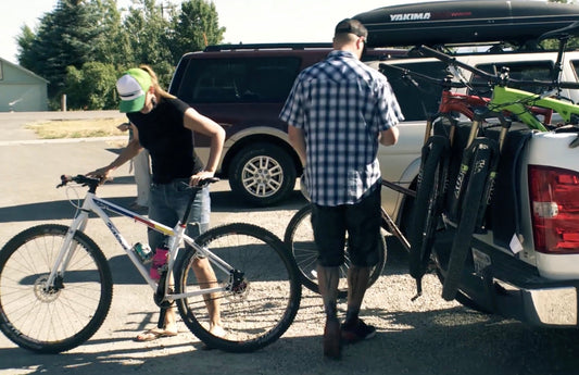 Riders unload their bikes from the back of a pickup truck.