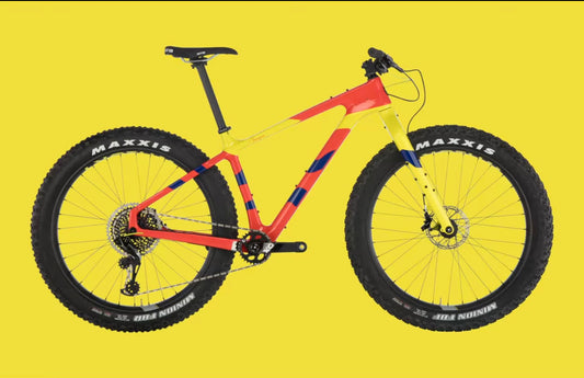 A yellow and red Salsa Beargrease fatbike sits against a solid yellow background.