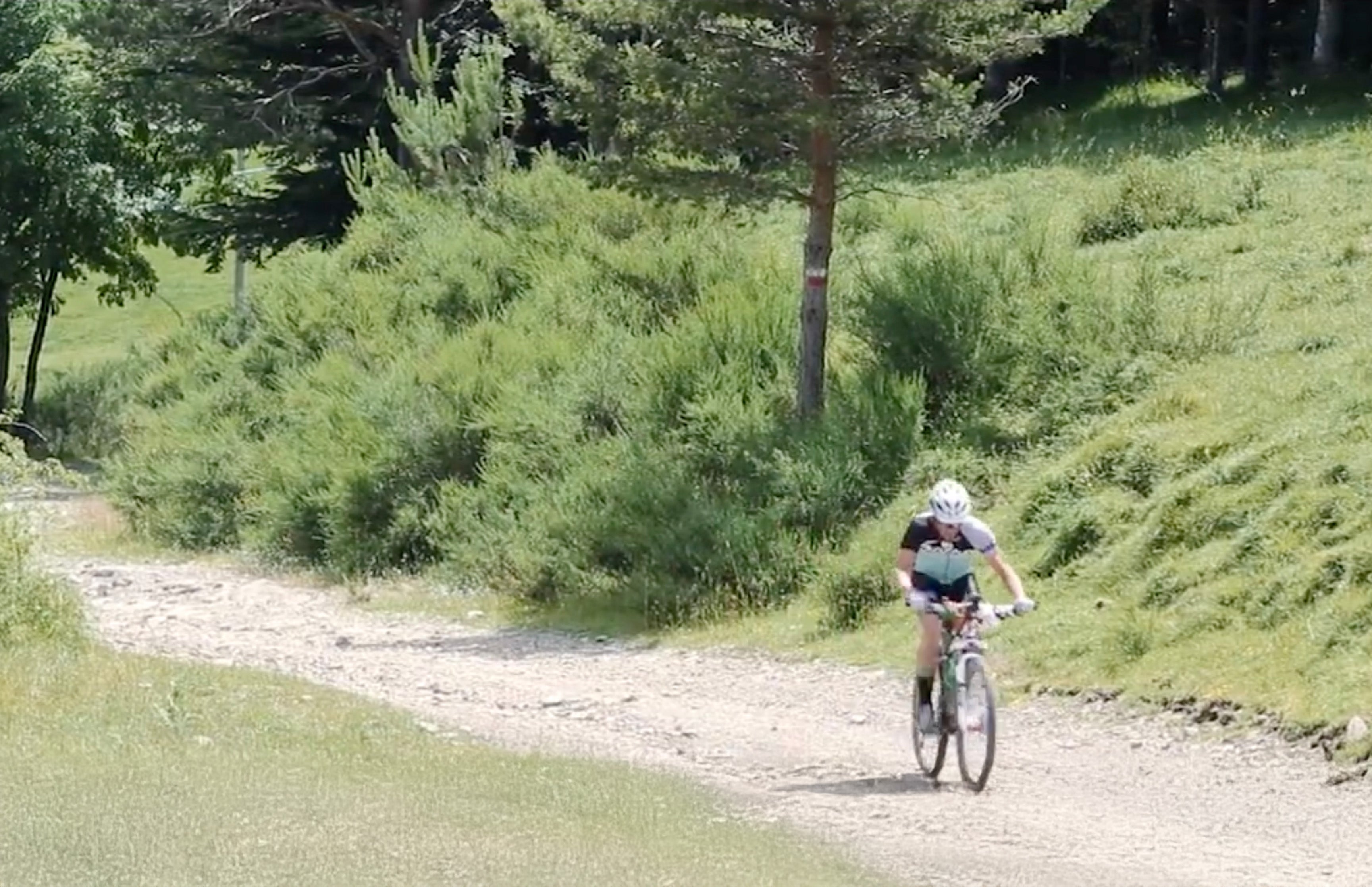 Cyclist in the distance rides a drop bar bike on a gravel trail.