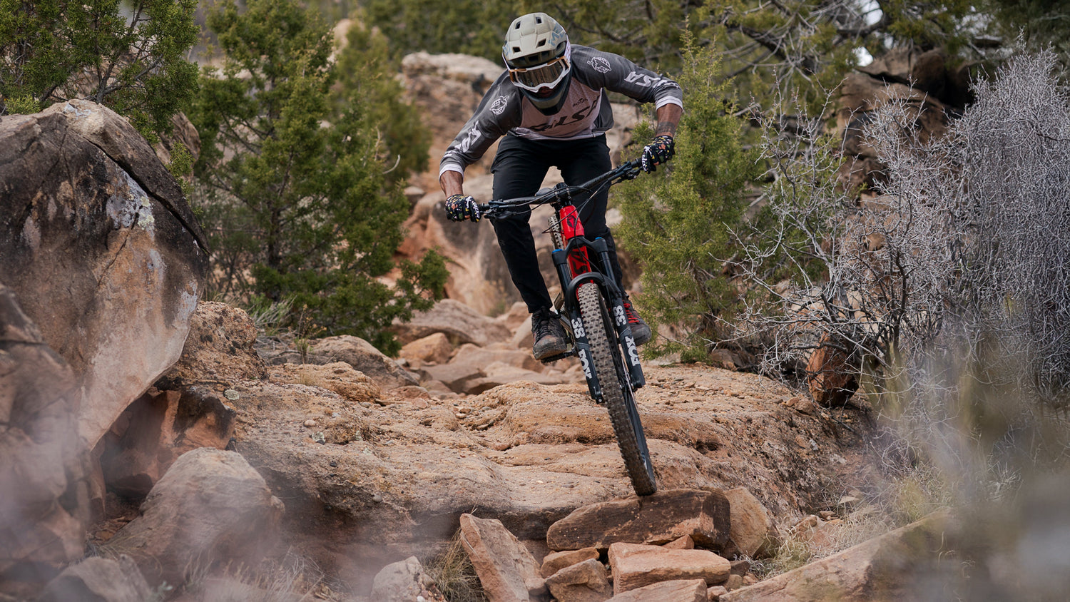 Mountain biker rides a Salsa Cassidy full suspension bike over rocky terrain.