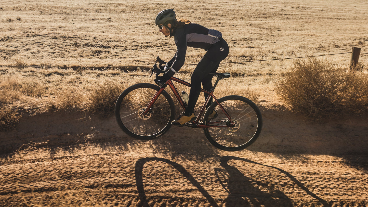 Cyclist gets air while riding on a dirt trail on their Salsa Stormchaser drop bar bike.