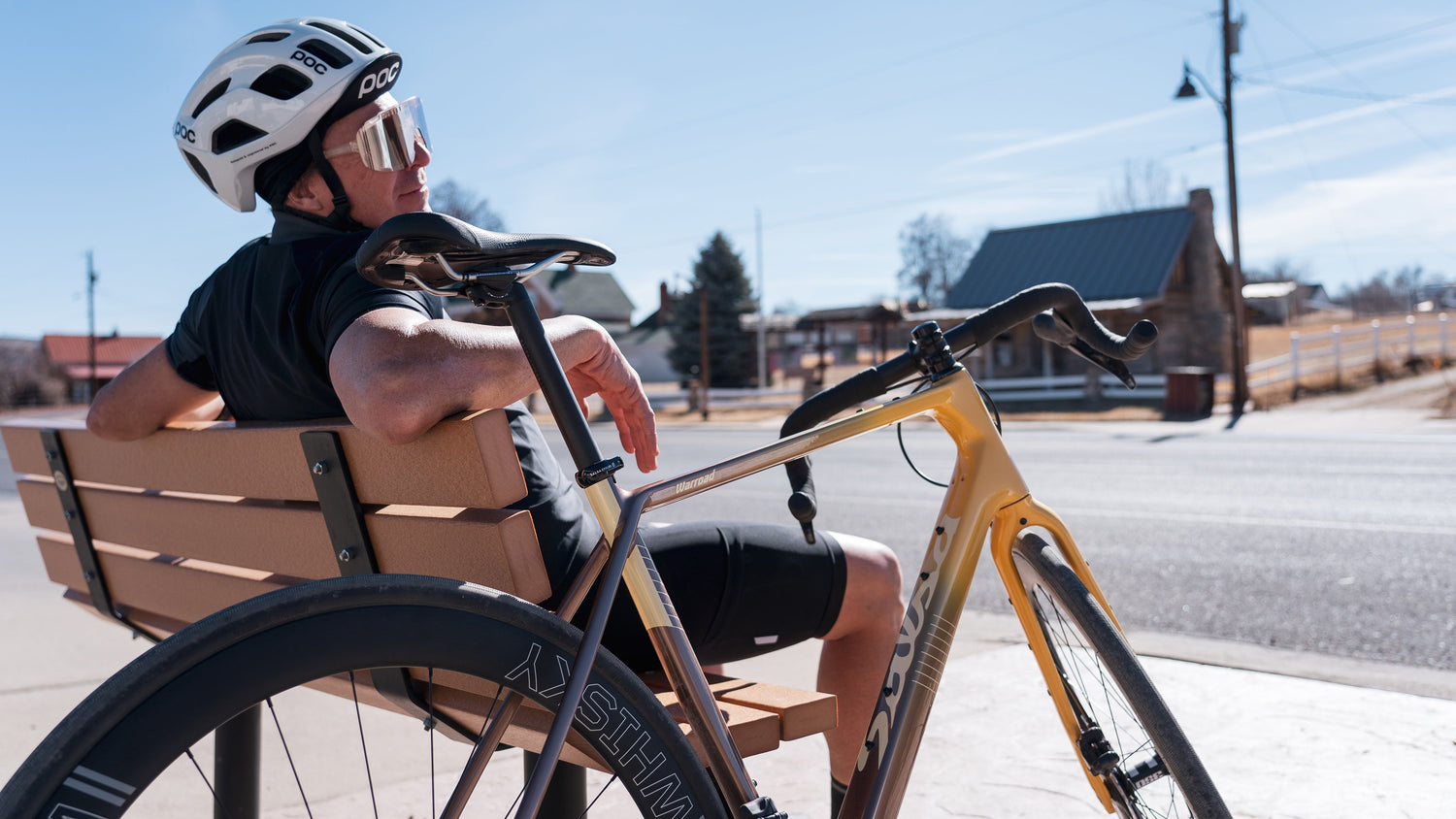 Cyclist takes a break on a bench. Their Salsa Warbird drop bar bike leans agains the bench.