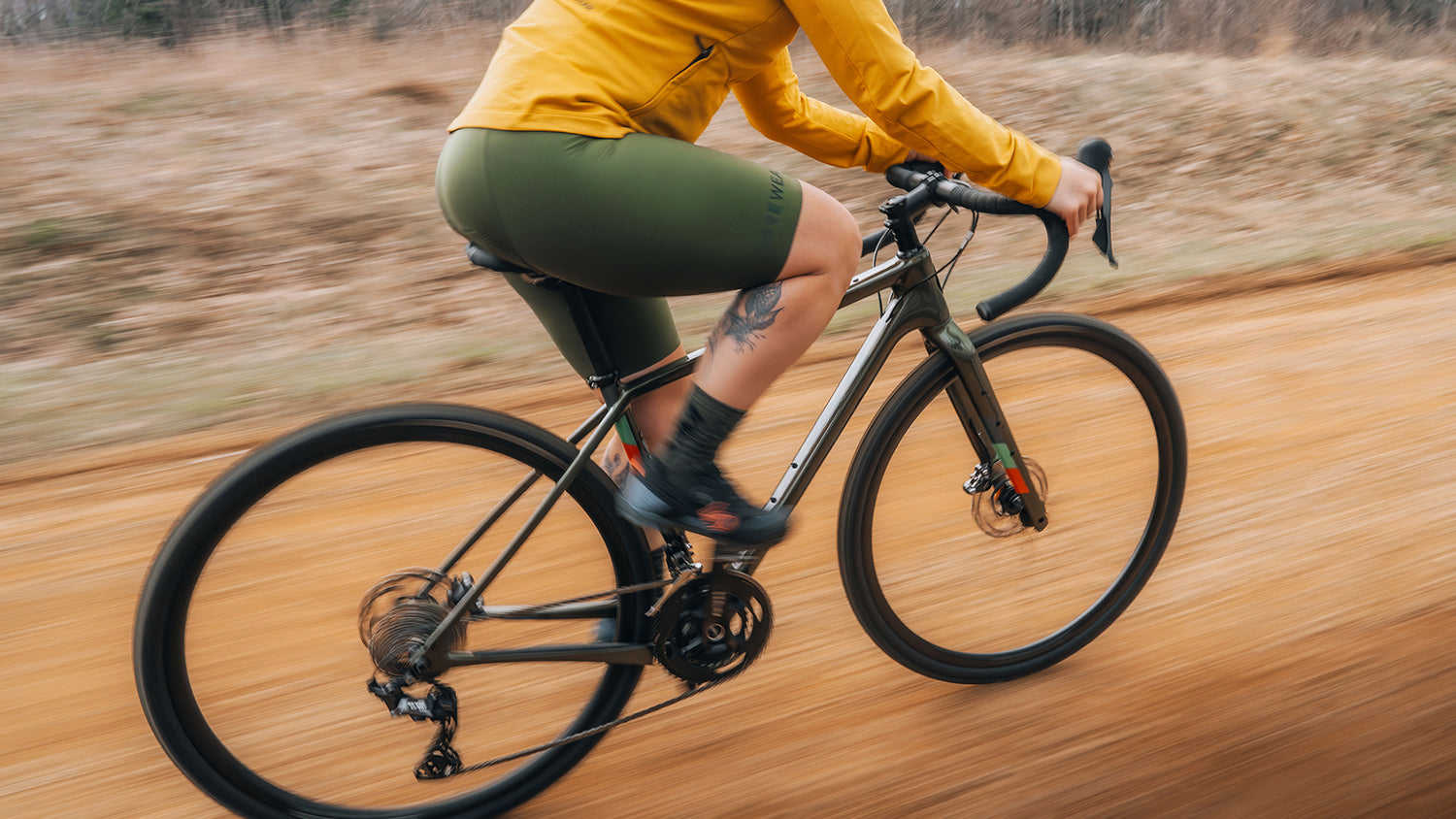 Cyclist in a yellow jacket rides a Salsa drop bar bike on a gravel road